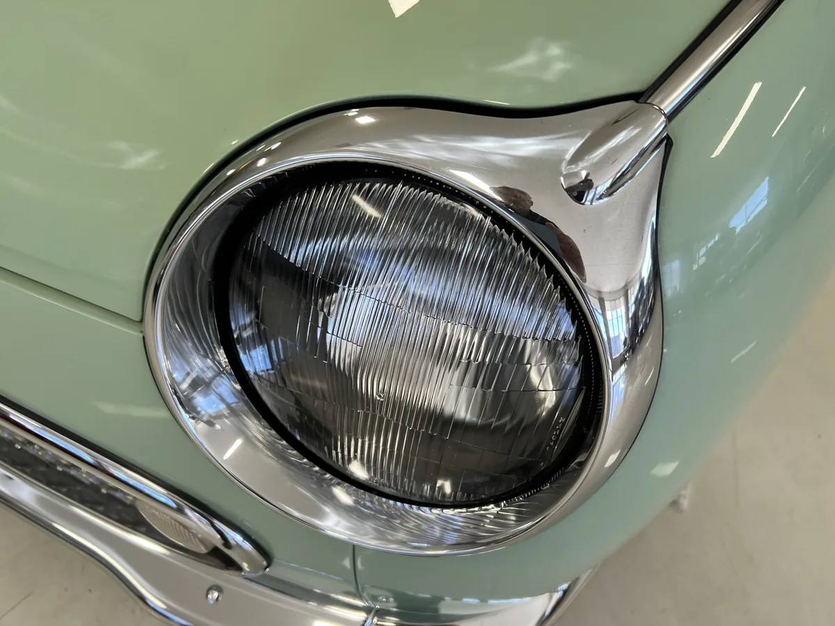 Round chrome-rimmed headlight on a Nissan Figaro