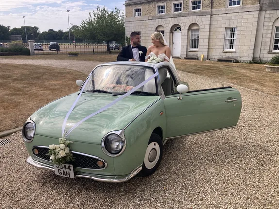 Bride and groom beside a Nissan Figaro wedding car at Woolverstone Hall, Ipswich