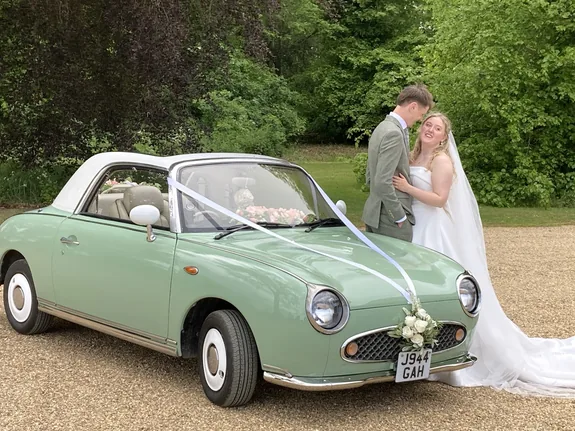 Bride and groom with a Nissan Figaro wedding car at Curds Hall Barn, Dereham, Norfolk