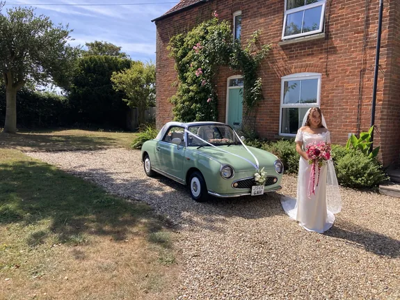 Bride beside a Nissan Figaro wedding car at Sea Palling on the Norfolk coast