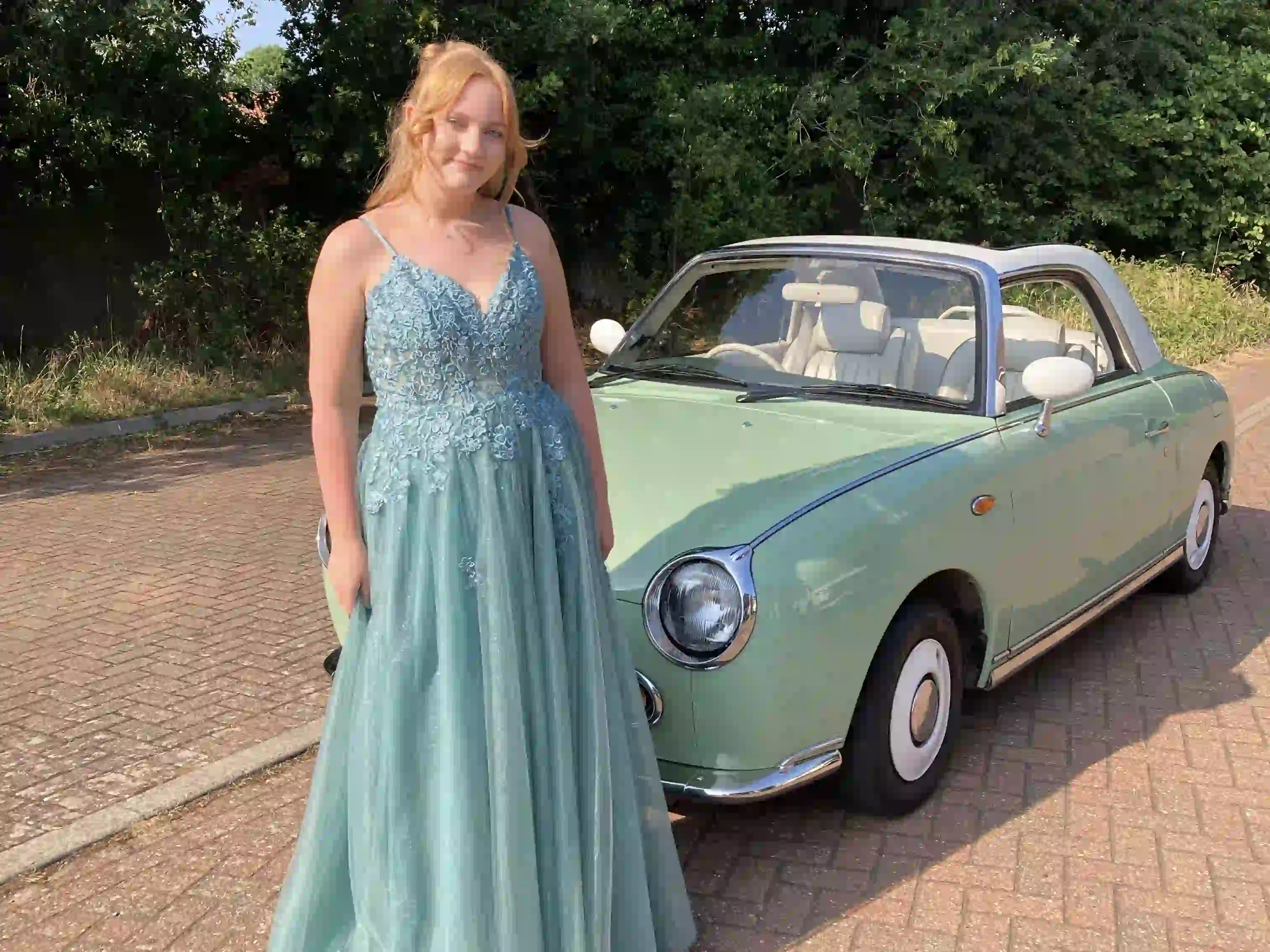 Hollie in a prom dress in front of a Nissan Figaro prom car