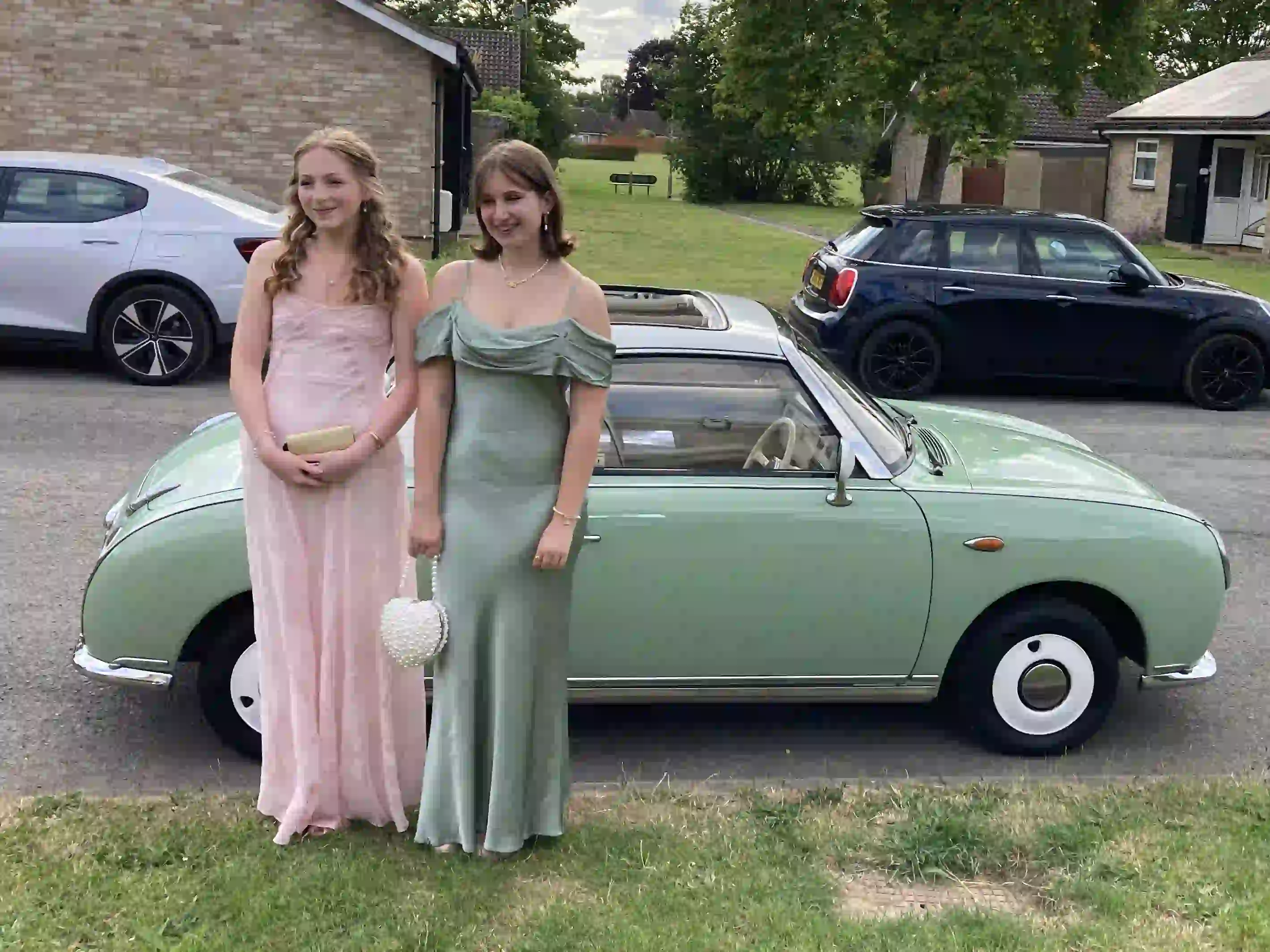 Jessica and Imogen standing together beside a Nissan Figaro prom car before their Sawston Village College prom