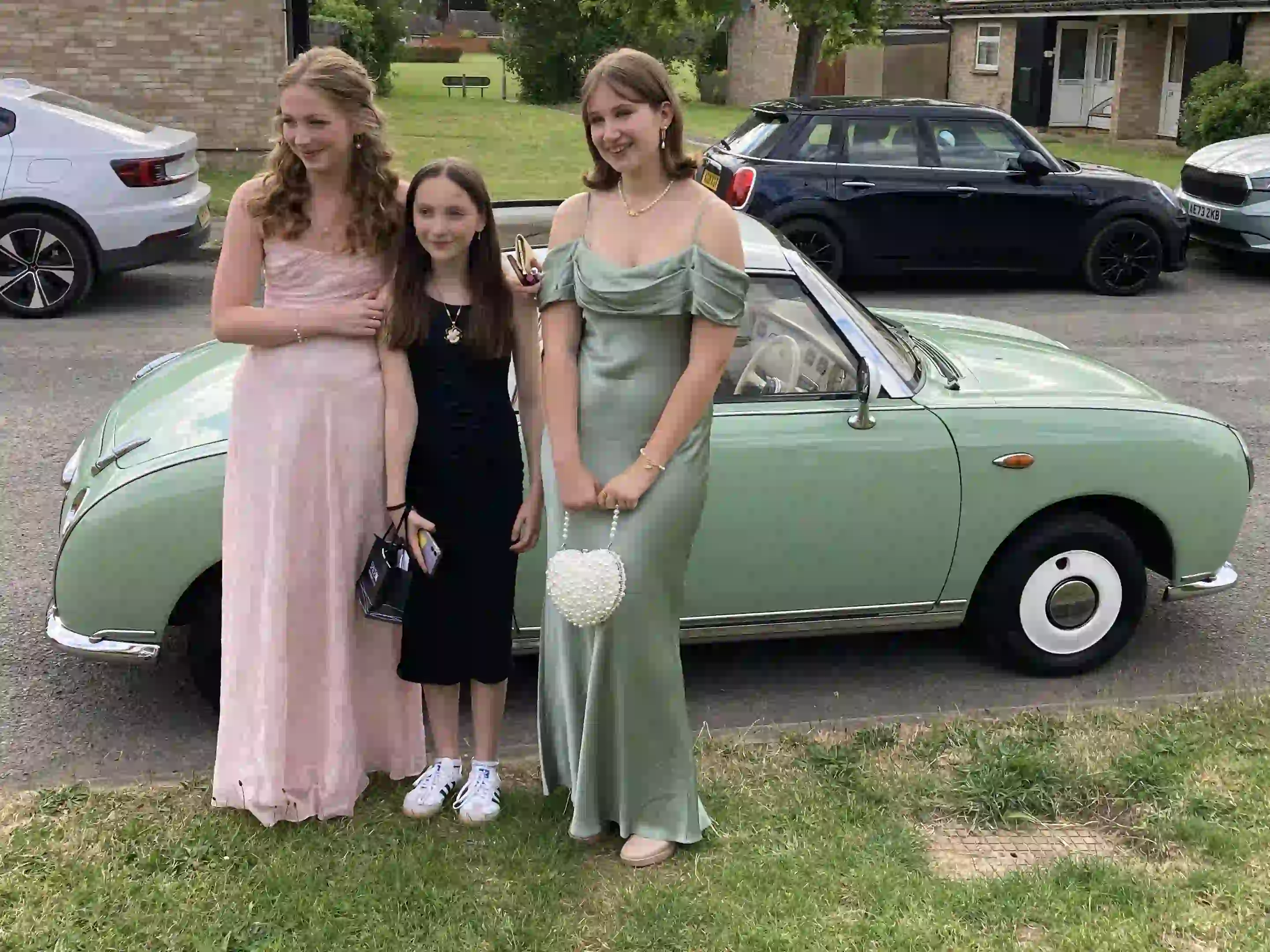 Jessica and Imogen with a younger sister beside a Nissan Figaro prom car before their Sawston prom