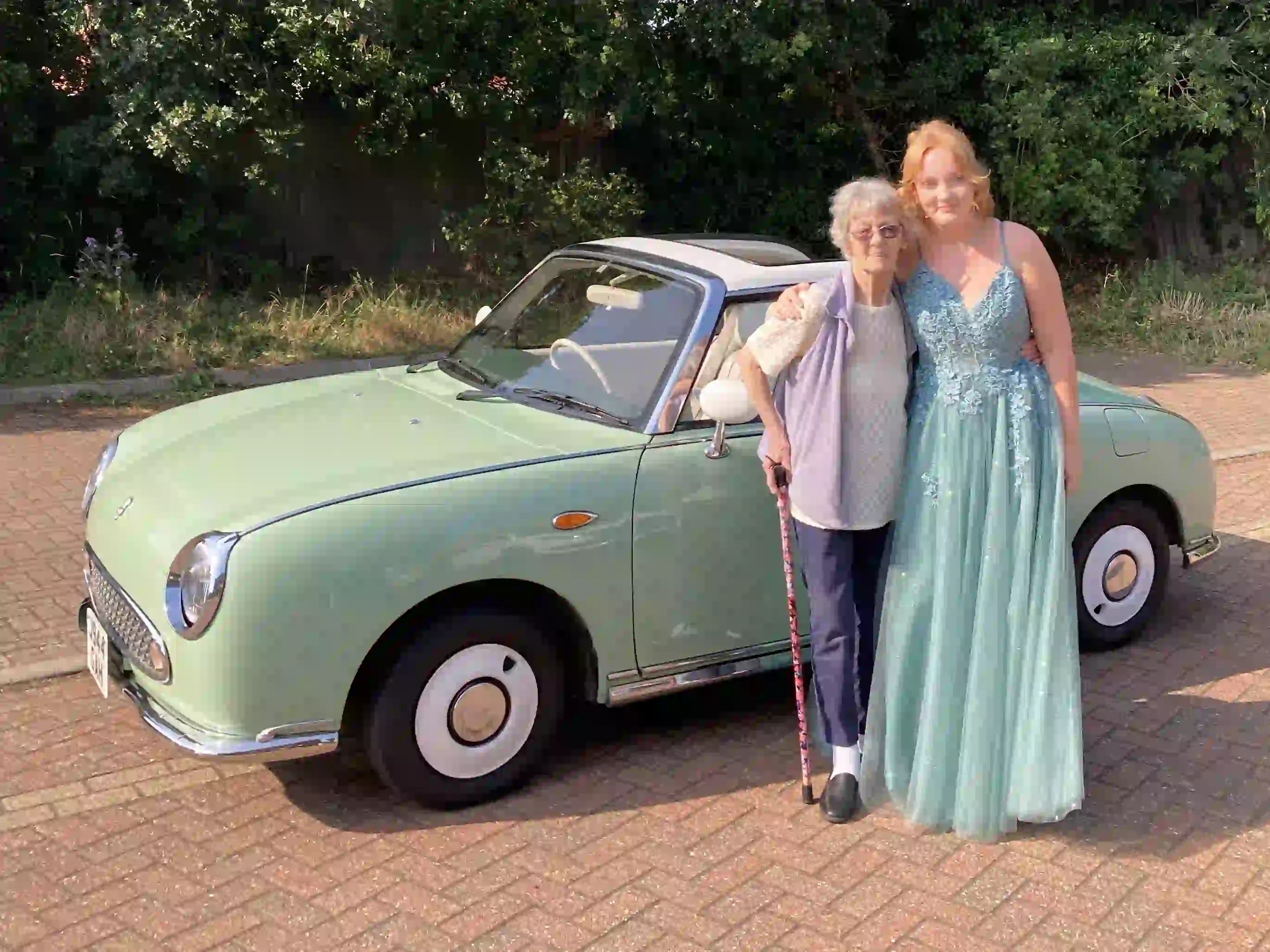 Hollie in her prom dress with her grandma beside a Nissan Figaro prom car