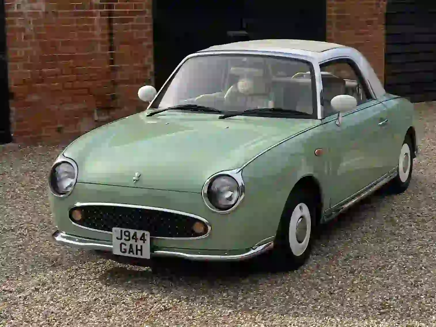 Mint green Nissan Figaro convertible for prom car hire, parked with the roof up and no wedding ribbons