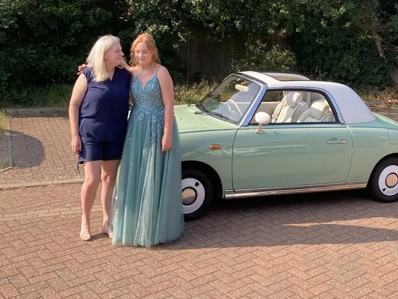 Girl in a prom dress with a Nissan Figaro prom car before a prom