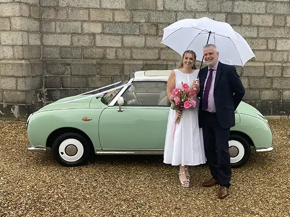 Bride and her father beside a Nissan Figaro wedding car before a Norwich Castle wedding